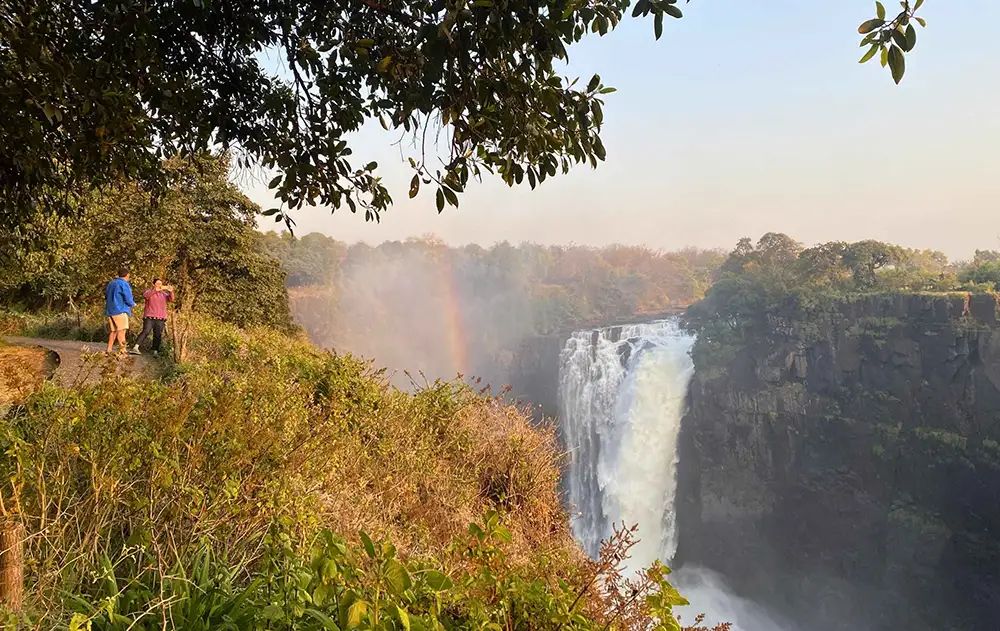Guide with guests at one of the numbered viewpoints - Falls curtain and spray in background, green rainforest framing. Avoid direct midday light - early morning or overcast preferred.
