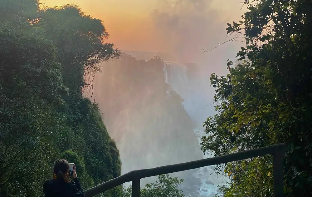 Guide and guests at one of the numbered viewpoints — Falls curtain and mist in background, green rainforest framing. Early morning or overcast preferred.