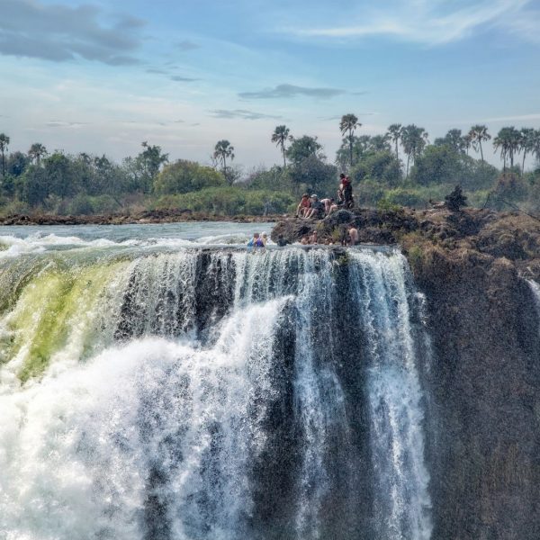 People sitting at the waterfall in Livingstone Island